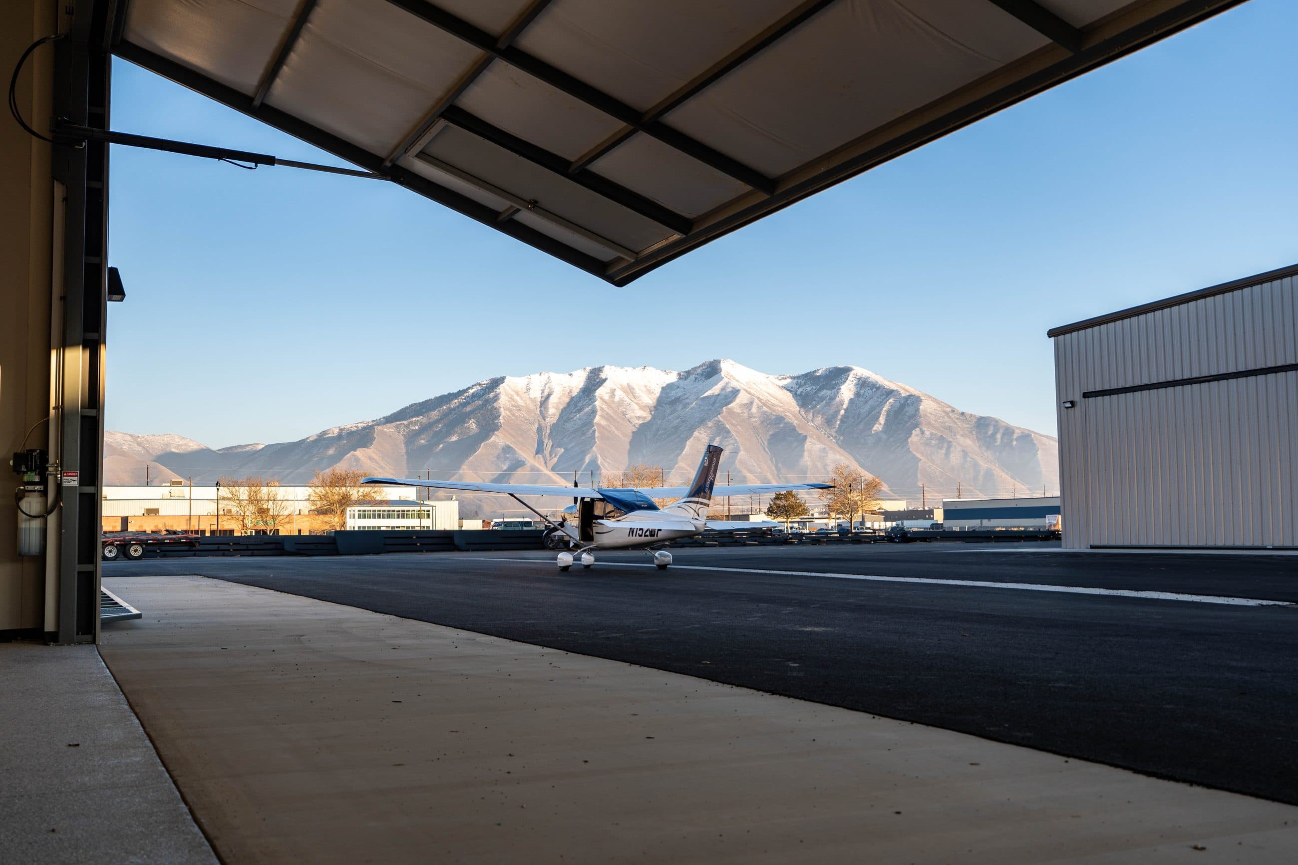 A Cessna on the ramp at Spanish Fork Airport, framed by an open hangar door